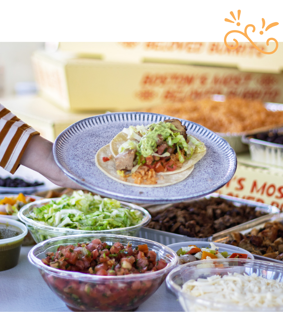 Anna’s Catering taco bar with a chicken taco being assembled with fresh toppings like lettuce, tomatoes, and cheese.