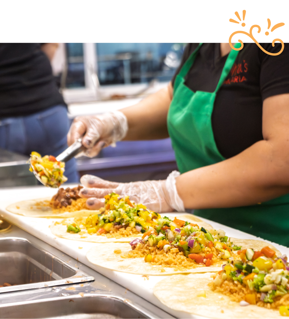 Anna's kitchen line creating a row of burritos filled with fresh ingredients