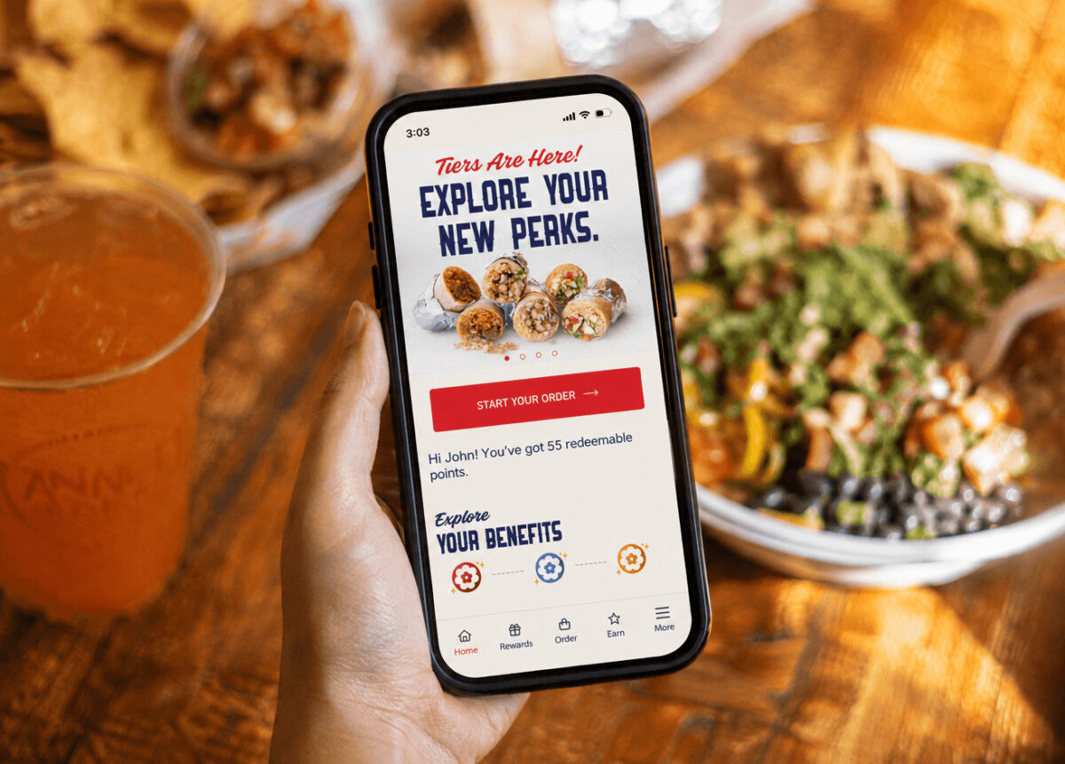 Anna’s Taqueria mobile app displayed on a smartphone with a burrito bowl, chips and drink in the background
