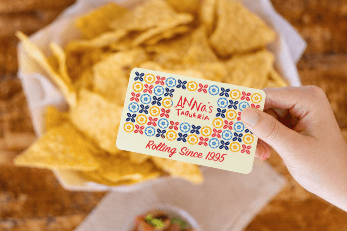Image of an Anna's Taqueria gift card with chips and salsa on the table in the background
